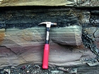 Alternating lenticular sheets of sand and shale that accumulated within fining upward deepwater turbidite fans with sparse channeling expressed by cut and fill. Note classic Bouma cycles of fill.